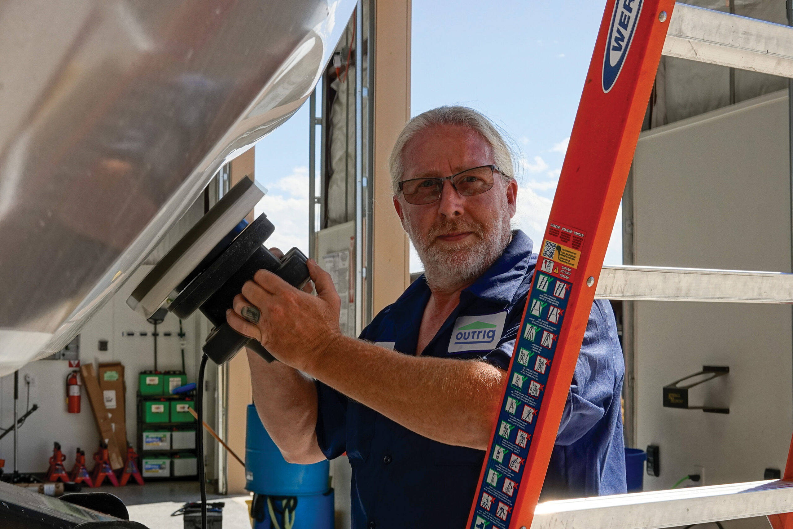 RV technician with white hair and beard working on a rig