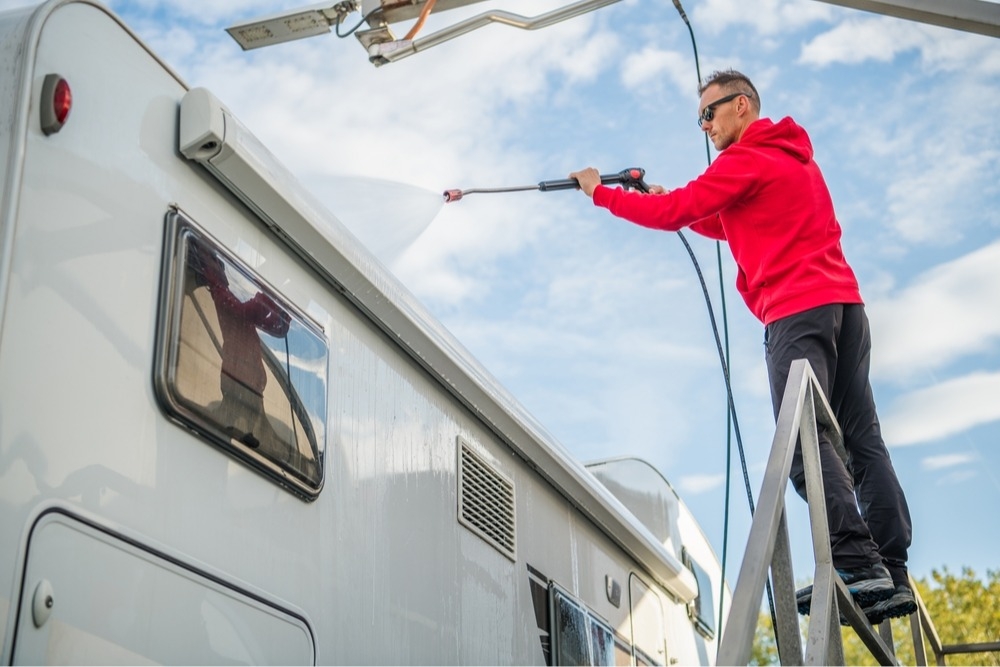 Man using hose and sprayer to clean RV roof