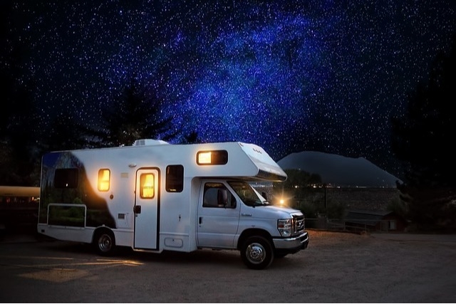 RV with interior lights turned on against a beautiful, starry night sky