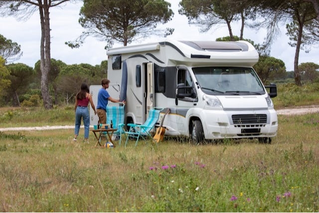 Couple setting up a camp outside of their parked RV.