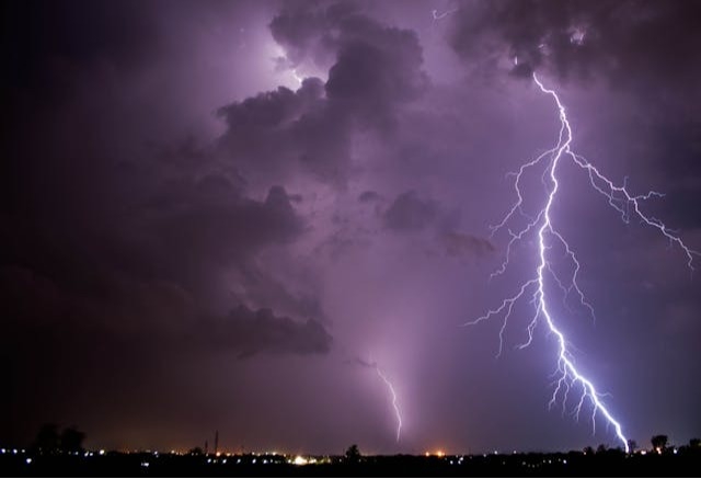 Horizon and dark night sky with a large bolt of lightning.