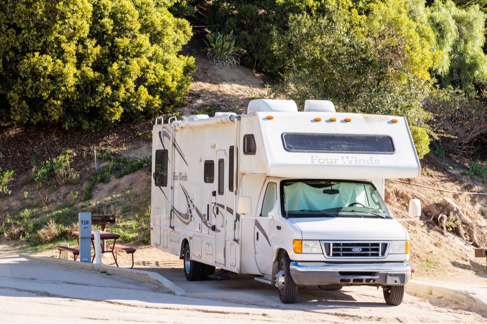 RV parked at a basic campsite with a picnic table.