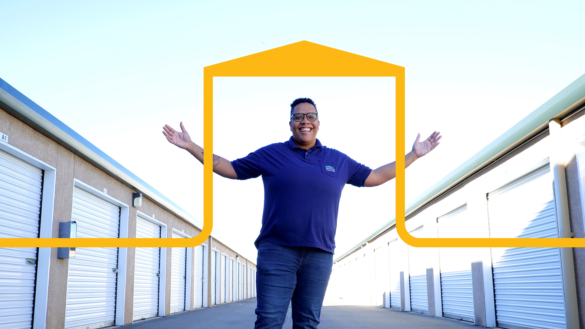 Smiling property manager wearing a blue shirt with the Outrig logo standing with her arms open, gesturing to enclosed garages to her left and right