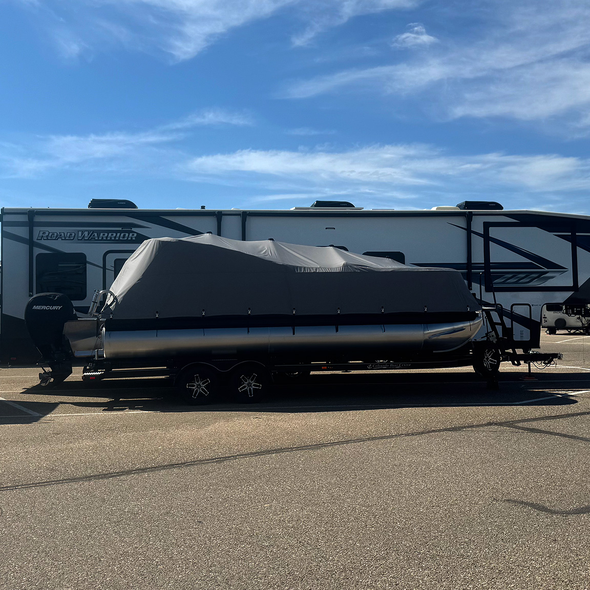 Boat with tarp covering it, parked in a paved outdoor storage space.